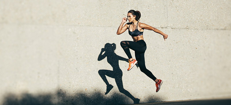 Woman running next to a wall