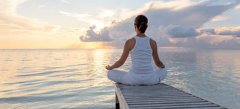 Ultimate guide, woman meditating on a sea dock, sunset clouds